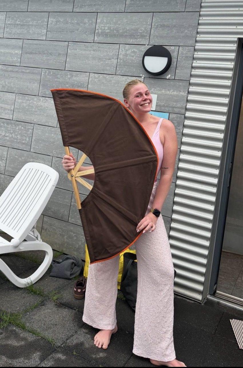 Kona heldur á stórum blævæng fyrir gusu